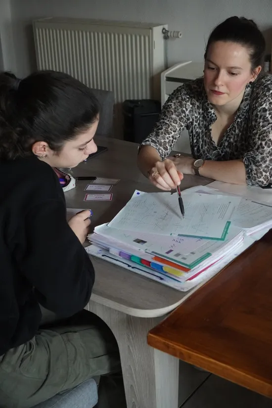 Enfant écrivant dans un cahier de mathématiques sur une table en bois