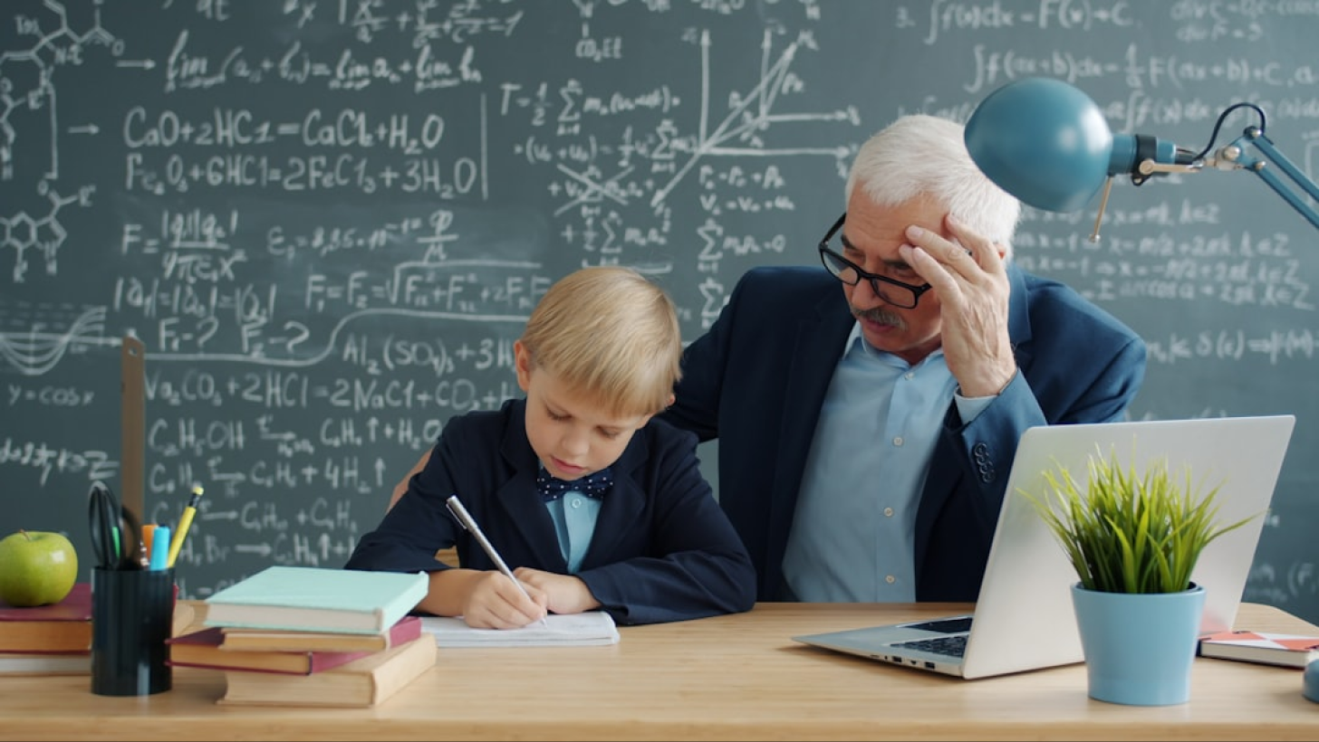 Professeur de mathématiques enseignant à un élève devant un tableau noir avec des formules mathématiques